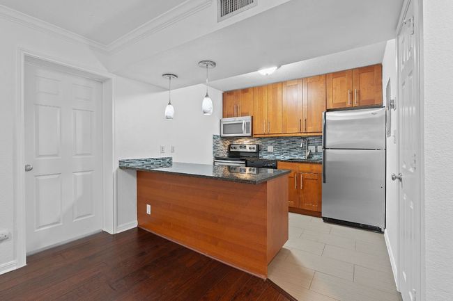 Kitchen with visible vents, decorative backsplash, brown cabinets, a peninsula, and stainless steel appliances | Image 17