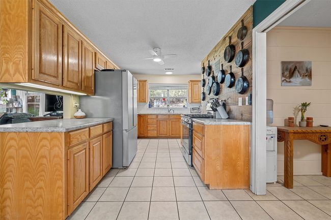 Kitchen featuring a ceiling fan, a textured ceiling, light tile patterned floors, light countertops, and appliances with stainless steel finishes | Image 12