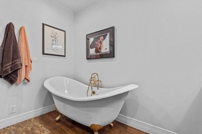 MAIN: Full bathroom featuring crown molding, baseboards, wood finished floors, and a freestanding tub | Image 17