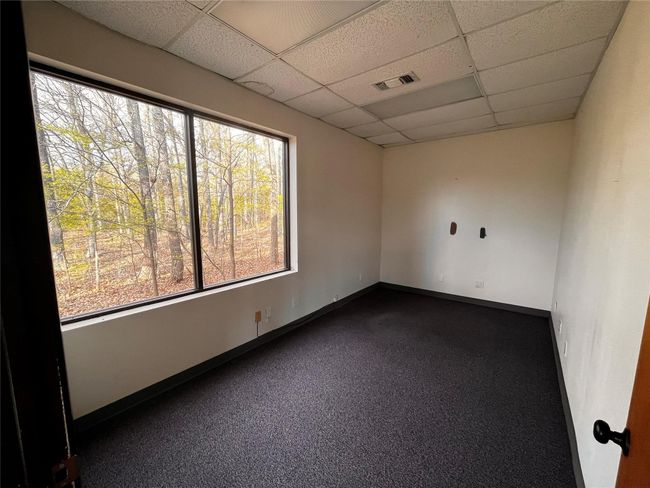 Unfurnished room featuring dark carpet, a paneled ceiling, visible vents, and a wealth of natural light | Image 17