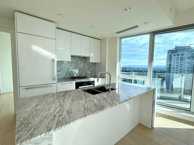 Kitchen featuring light wood finished floors, modern cabinets, white cabinetry, a sink, and built in fridge | Image 7