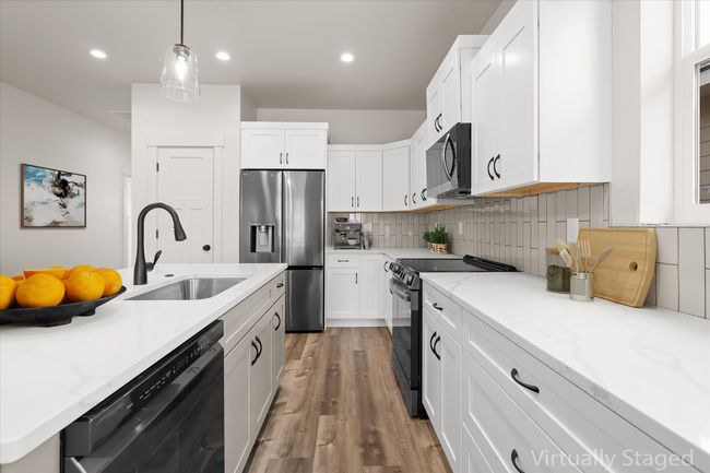 Kitchen with light wood-style flooring, backsplash, a sink, white cabinets, and black appliances | Image 6