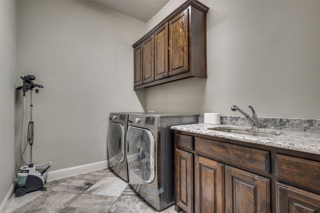 Laundry area featuring sink, washing machine and dryer, and cabinets | Image 25
