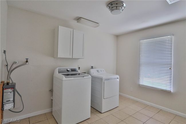 Laundry room with separate washer and dryer, cabinet space, baseboards, and light tile patterned floors | Image 27