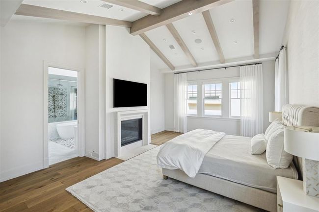 The breathtaking primary bedroom is a private retreat, exuding serenity and sophistication. Majestic white pine ceiling beams complement the abundant natural light. Expansive windows enhance the suite’s elegance, offering stunning green views that create a dreamy and tranquil ambiance. | Image 15