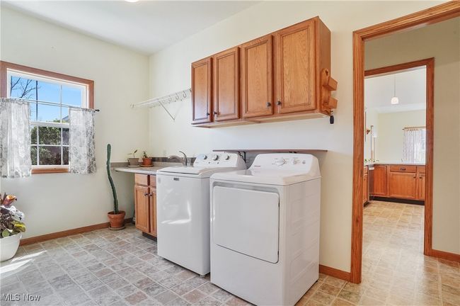 Laundry room featuring baseboards, washer and clothes dryer, stone finish flooring, and cabinet space | Image 39