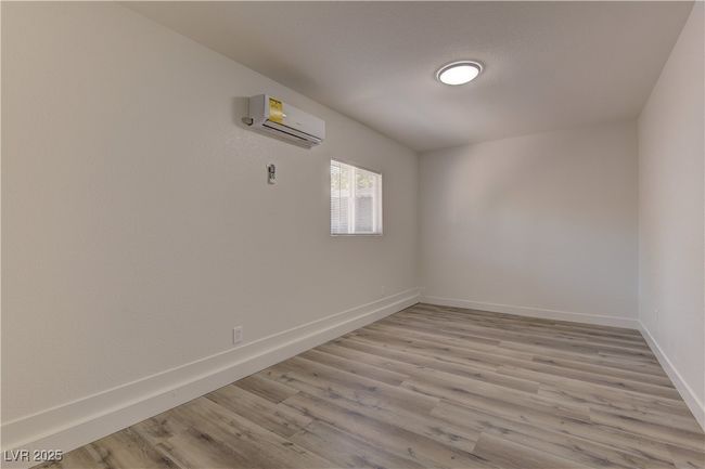 Unfurnished room featuring a wall unit AC, baseboards, and light wood finished floors | Image 28