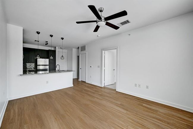 Unfurnished living room with baseboards, a ceiling fan, wood finished floors, and visible vents | Image 6