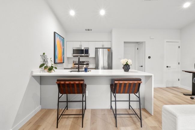 Kitchen with appliances with stainless steel finishes, white cabinets, light wood-style flooring, light countertops, and recessed lighting | Image 6