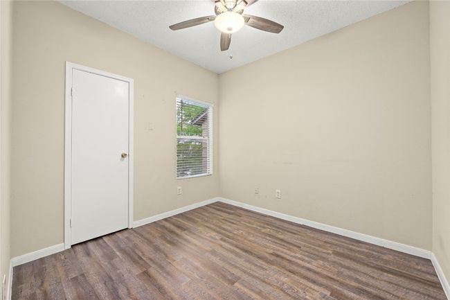 Empty room with wood finished floors, a ceiling fan, baseboards, and a textured ceiling | Image 12