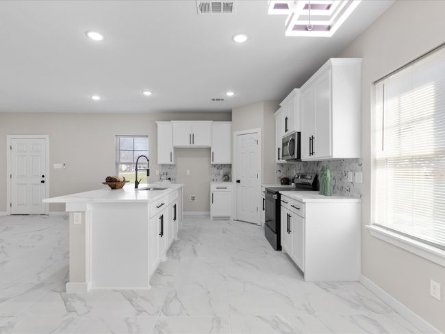 Kitchen with visible vents, a sink, range with electric cooktop, stainless steel microwave, and tasteful backsplash | Image 11
