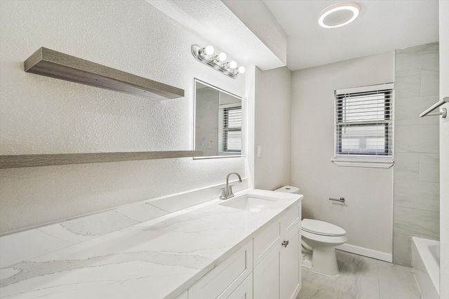 Bathroom with a textured wall, baseboards, toilet, vanity, and marble finish floor | Image 28