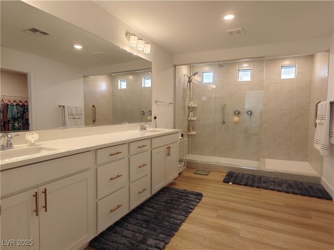 Bathroom featuring wood finished floors, visible vents, tiled shower, and a sink | Image 35
