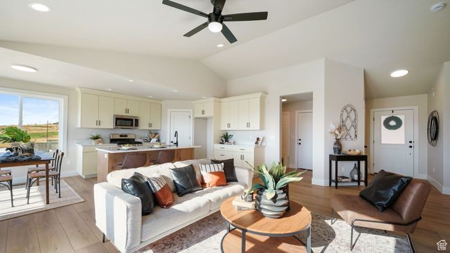 Living room featuring light wood finished floors, a ceiling fan, vaulted ceiling, and recessed lighting | Image 7