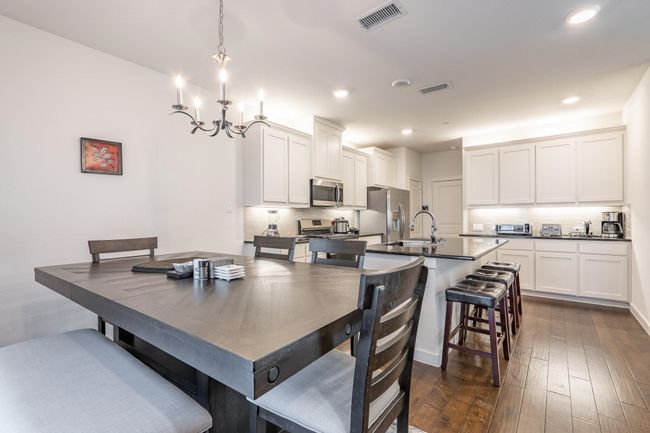 Dining room featuring a notable chandelier, dark wood-style floors, visible vents, and recessed lighting | Image 4