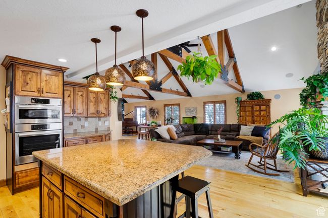 Kitchen featuring a kitchen island, tasteful backsplash, double oven, light wood-type flooring, and vaulted ceiling with beams | Image 11