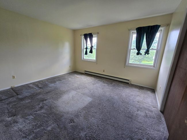 Spare room with a baseboard radiator, plenty of natural light, carpet, and baseboards | Image 8