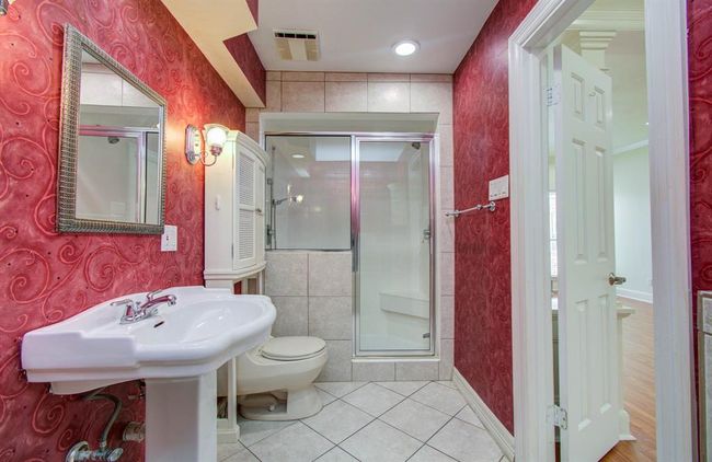 Luxurious primary bath featuring a sleek pedestal sink, a modern glass-enclosed shower, and stylish lighting. | Image 19
