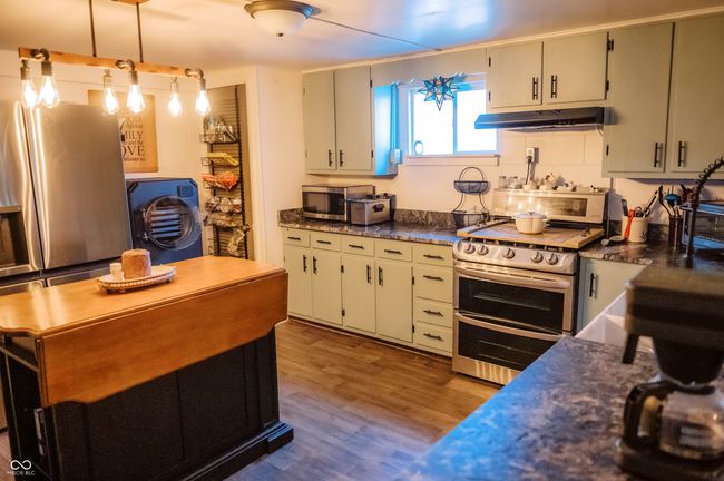 kitchen featuring dark countertops, appliances with stainless steel finishes, dark wood-style floors, and under cabinet range hood | Image 22