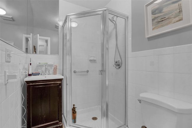 Bathroom with toilet, tile walls, vanity, and a shower with door | Image 18