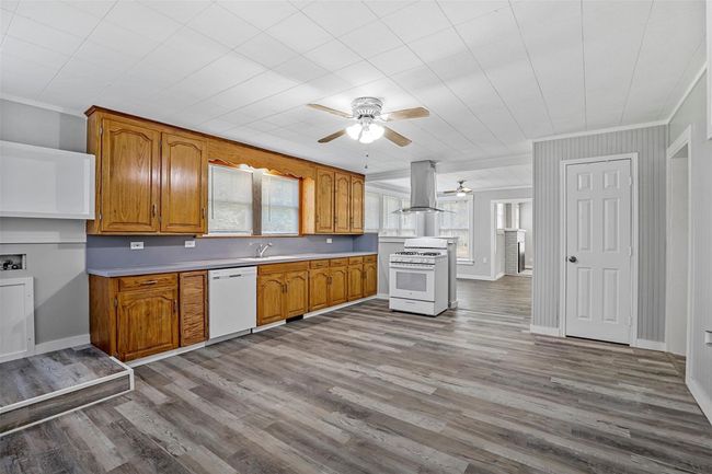 Kitchen with ceiling fan, brown cabinetry, ornamental molding, light countertops, and white appliances | Image 8