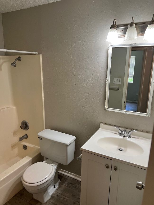 Bathroom featuring wood finished floors, toilet, vanity, shower / washtub combination, and baseboards | Image 14