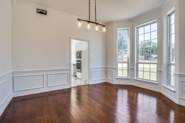 Unfurnished dining area featuring hardwood / wood-style flooring, crown molding, wainscoting, and a decorative wall | Image 5