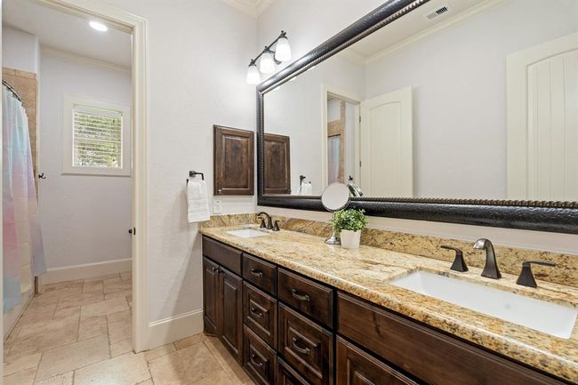 The second and third Secondary Bedrooms share this spacious bathroom equipped with dual undermount sinks, granite countertop, framed mirror, medicine cabinet, and tile flooring. Through the privacy of the second door, you will find a linen closet, toilet, and shower/tub combo that features an extra-large storage cubby. | Image 38