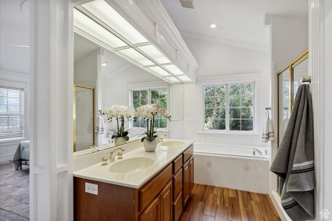 Full bathroom featuring a bath, double vanity, wood finished floors, crown molding, and a shower with door | Image 17