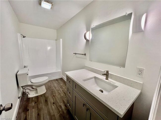 Bathroom featuring washtub / shower combination, wood finished floors, toilet, and vanity | Image 26