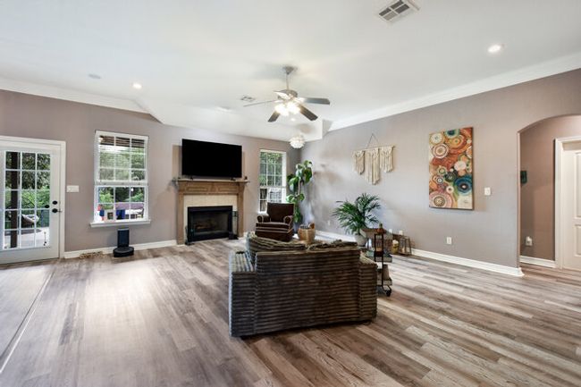 Living area featuring a fireplace, light wood-style flooring, a ceiling fan, arched walkways, and crown molding | Image 4