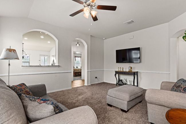 Living area featuring arched walkways, ceiling fan, visible vents, and carpet floors | Image 5