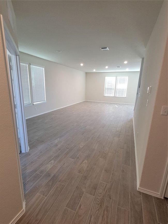 Empty room with wood finished floors, recessed lighting, baseboards, and visible vents | Image 10