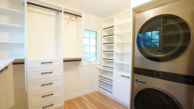 Two large windows provide ample natural light in the owner's private walk in closet. Luxurious touches abound including upper level laundry, tilted shoe display shelves, large pull-out hamper, soft-close drawers, ample shelving and hanging rods. | Image 5