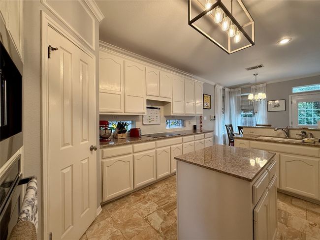 Kitchen with an inviting chandelier, a sink, a center island, visible vents, and ornamental molding | Image 8