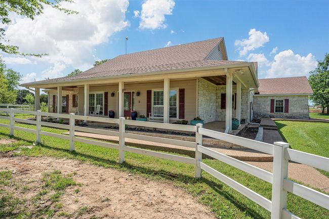 View of front of home with a shingled roof, stone siding, and covered porch | Image 7