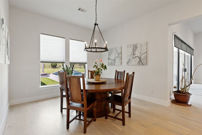 Dining area featuring a chandelier, visible vents, light wood-type flooring, and baseboards | Image 13