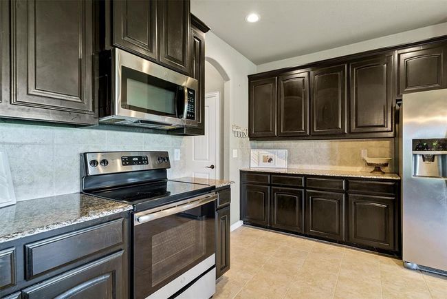 Kitchen featuring stainless steel appliances, light stone countertops, tasteful backsplash, and light tile floors | Image 14