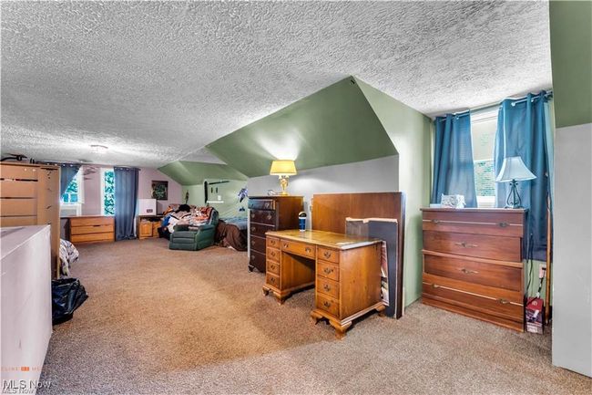 Bedroom featuring a textured ceiling, carpet floors, multiple windows, and lofted ceiling | Image 24