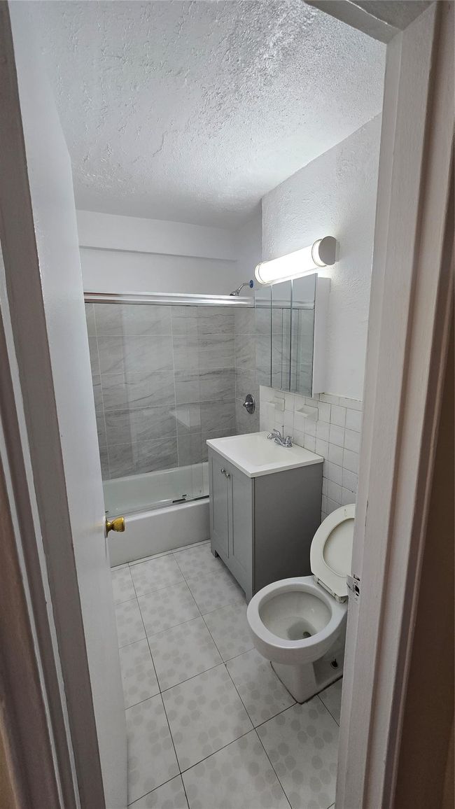 Bathroom featuring tile walls, vanity, shower / tub combination, a textured ceiling, and tile patterned floors | Image 12