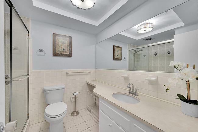 Your Bathroom Has an Updated Glass Enclosed Shower, Huge Custom Mirror, Built-In Hamper, Wall Heater and lots of Storage Cabinets and Countertops. | Image 8