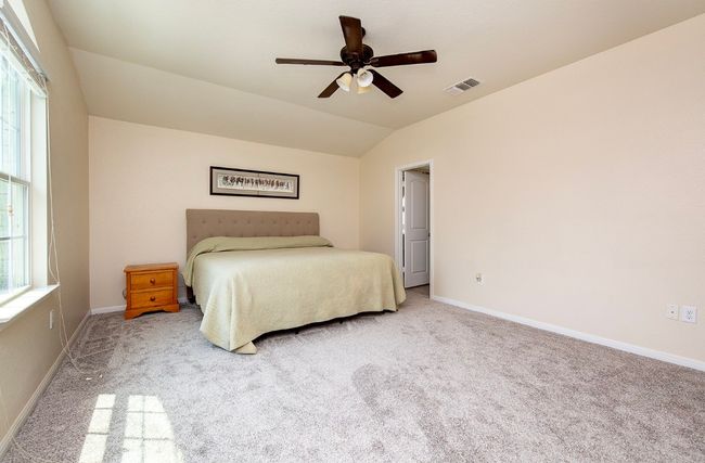 Bedroom with carpet, baseboards, vaulted ceiling, and a ceiling fan | Image 14