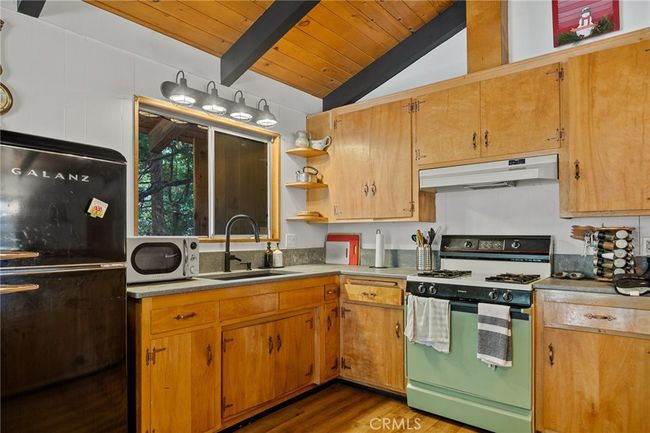 Kitchen with pine kitchen cabinets and knotty pine ceilings. | Image 7