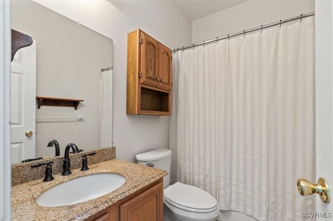 Bathroom with toilet, vanity, and a shower with shower curtain | Image 34