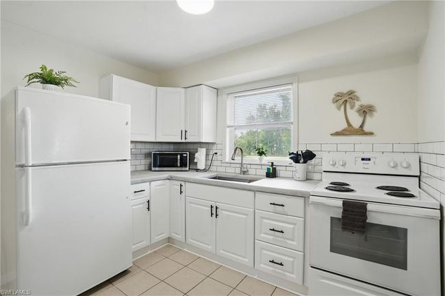Kitchen featuring white appliances, light tile patterned flooring, backsplash, and light countertops | Image 22