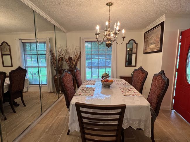 Dining room with baseboards, ornamental molding, an inviting chandelier, and a textured ceiling | Image 8