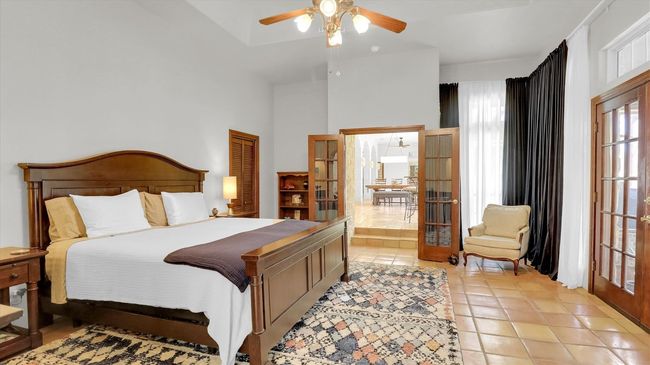 One of two Primary Bedrooms featuring french doors, ceiling fan, and light saltillo tile flooring | Image 24