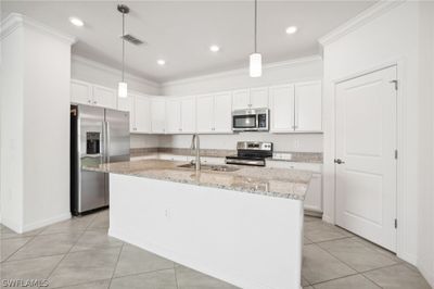 Kitchen with appliances with stainless steel finishes, light tile patterned floors, pendant lighting, and an island with sink | Image 3