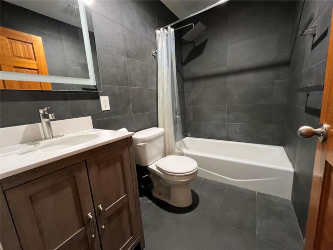 Full bathroom with vanity, tile patterned floors, shower / bath combination with curtain, toilet, tile walls and lighted mirror | Image 10