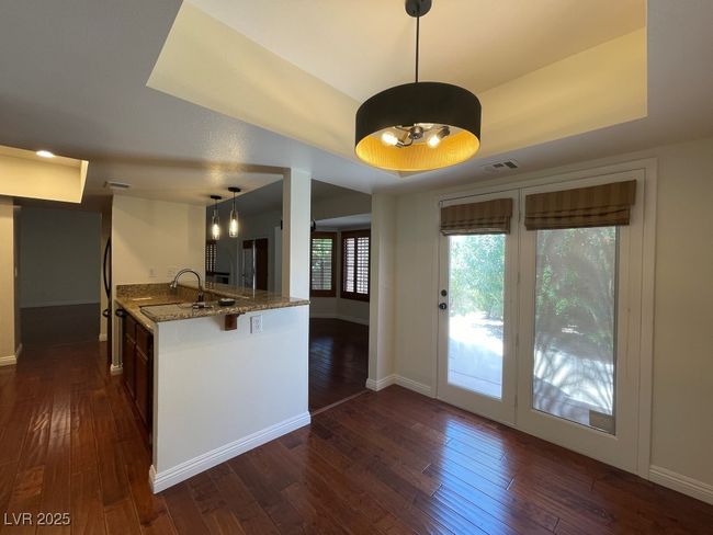 Kitchen with stone counters, dark wood-type flooring, a tray ceiling, and pendant lighting | Image 4